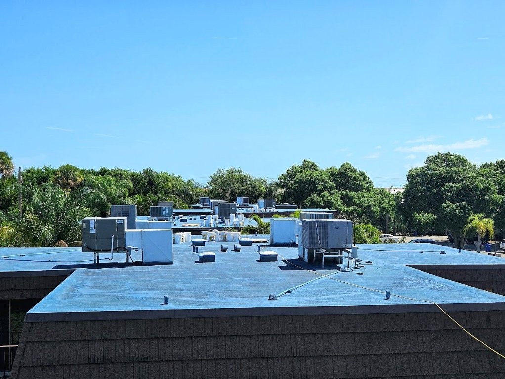 Flat roof before silicone coating showing seam failure and ponding water
